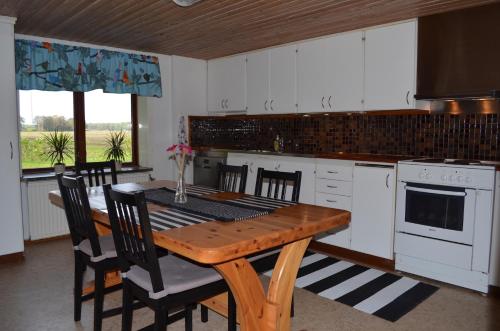 赫加奈斯Smedsgården的一间带木桌的厨房和一间带白色橱柜的厨房