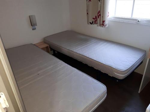 南莱潘Mobil Home Sainte Baume的小房间设有两张床和窗户