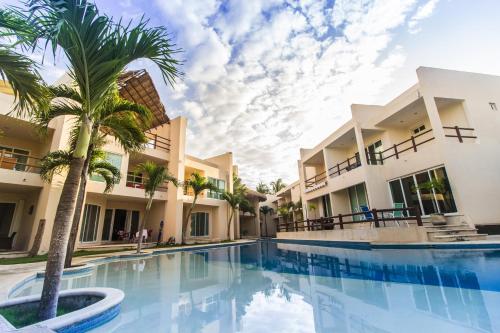 阿文图拉斯港Coral Maya Stay Suites的棕榈树建筑前的游泳池