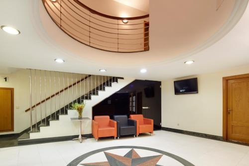 扎鲁亚斯谢基贝吉里特膳食酒店的大堂设有橙色椅子和螺旋楼梯