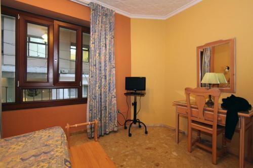 马拉加维多利亚旅馆的客房设有书桌、电视和椅子