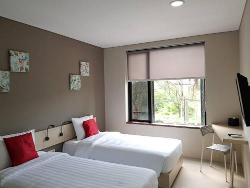 当格浪瓦拿度酒店的一间卧室设有两张床、一张桌子和一个窗口。