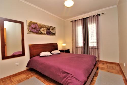 丰沙尔Apartamento Orquidea的一间卧室配有一张带镜子的紫色床和窗户。