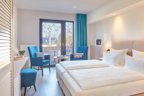 佩尔泽哈肯Familotel Strandkind的酒店客房带大床和蓝色椅子