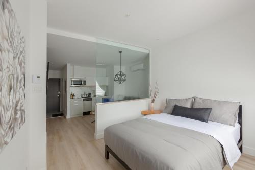 魁北克市Les Lofts Ste-Anne的一间白色卧室,配有一张大床和一个厨房