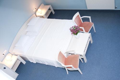 NemesnépAbbazia Country Club的一张带两把椅子的白色床和一张带鲜花的桌子