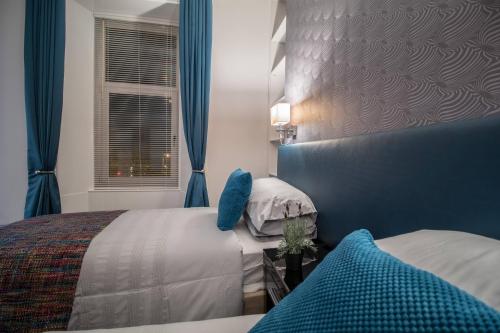 米尔盖West Highland Apartments Milngavie - The Lomond的一间卧室配有两张带蓝色窗帘的床和窗户。