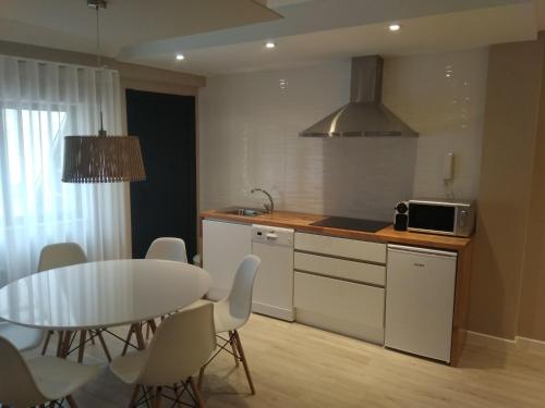 里瓦德奥Apartamento centro Ribadeo的厨房以及带桌子和桌椅的用餐室。