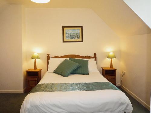 巴利巴宁Ballybunion Holiday Cottages的一间卧室配有一张大床和两盏灯