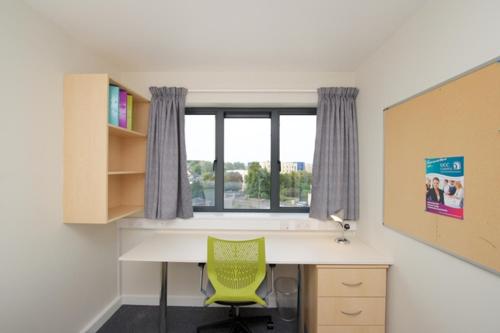 科克University Hall Apartments - UCC Summer Beds的带绿椅的书桌,位于带窗户的房间内