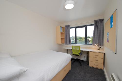 科克University Hall Apartments - UCC Summer Beds的一间卧室配有一张床和一张带绿椅的书桌