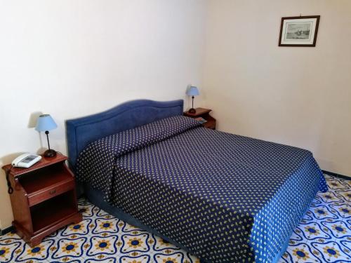波西塔诺La Taverna del Leone的一间卧室配有一张带蓝色棉被的床和一张桌子
