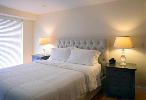波士顿布里克套房酒店的一间卧室配有一张带两盏灯的大型白色床。