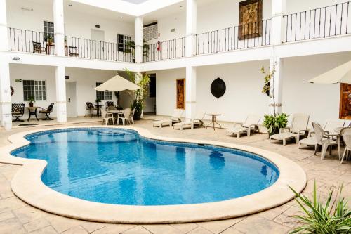 梅里达玛丽亚何塞酒店的庭院内的游泳池,配有桌椅