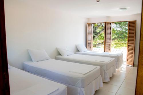 特林达迪Hotel Pousada Recanto do Pai的客房设有4张白色的床和窗户。