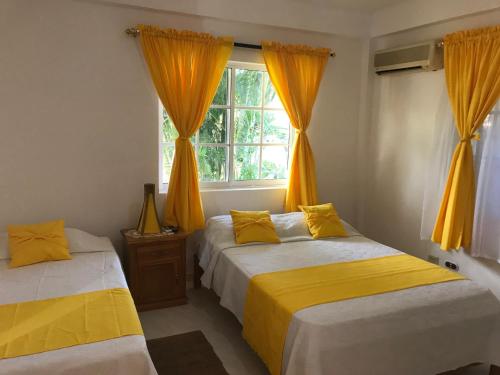 Santa Catalina Island阳光天堂宾馆的配有橙色窗帘和窗户的客房内的两张床