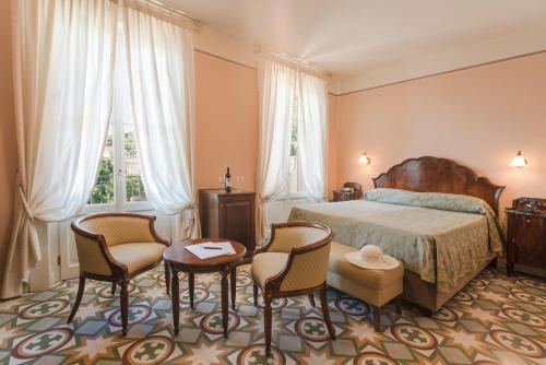 加尔尼亚诺Hotel Gardenia al Lago的一间卧室配有一张床、两把椅子和一张桌子