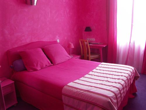 昂古莱姆帕莱斯酒店的粉红色的卧室配有一张床和一张桌子