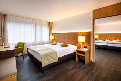 巴登Ramada by Wyndham Baden Hotel du Parc的酒店客房设有一张大床和一张书桌。