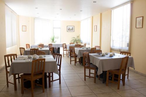 乔卢拉Villas Hotel Cholula的用餐室设有桌椅和窗户。