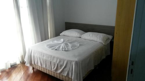 瓜拉普阿瓦Rocha's Hotel的一间卧室配有带白色床单和枕头的床。