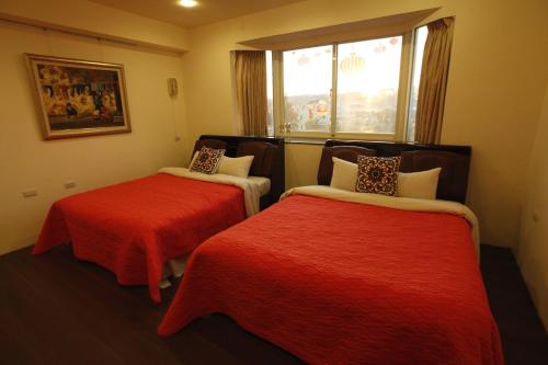 新社 花田民宿的客房设有两张带红色床单的床和窗户。