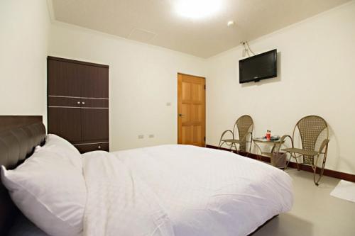 太麻里金仑乡村民宿 的卧室配有白色的床和墙上的电视。