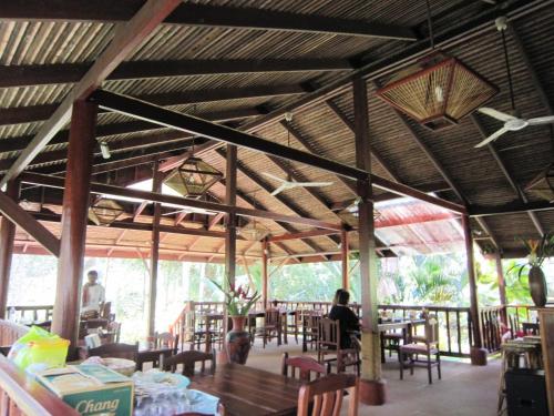 甲米镇帕侬栟茶避暑山庄的一间设有桌椅的餐厅,有坐在桌子上的人