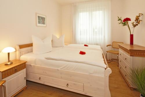 岑平Residenz Waldhaus_05的卧室配有白色的床铺,上面有红色的鲜花