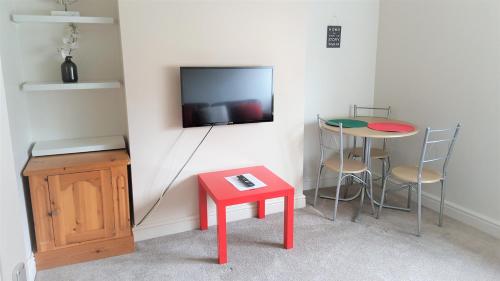 史云顿Swindon City Centre Duplex - EnterCloud9SA的一间设有红色桌子的房间和墙上的电视