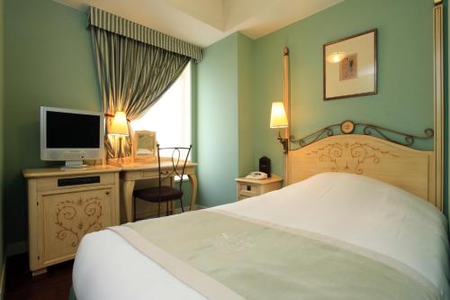 东京银座蒙特利拉苏瑞酒店的一间卧室配有一张床和一张书桌及电视