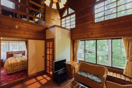 北斗市Izumigo AMBIENT Yatsugatake Cottage的小木屋内的卧室配有1张床和电视
