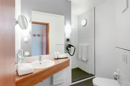 沃尔夫斯堡Hotel Wolfsburg Centrum, Affiliated by Meliá的白色的浴室设有水槽和卫生间。