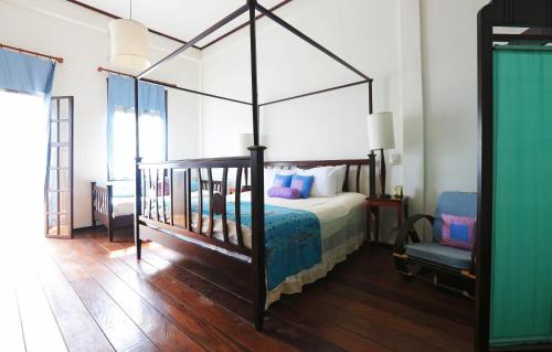 琅勃拉邦飞天酒店的一间卧室配有一张天蓬床和一把椅子