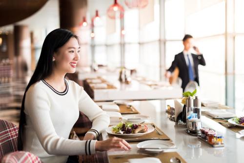 南京南京禄口机场铂尔曼大酒店的坐在餐桌上吃一盘食物的女人
