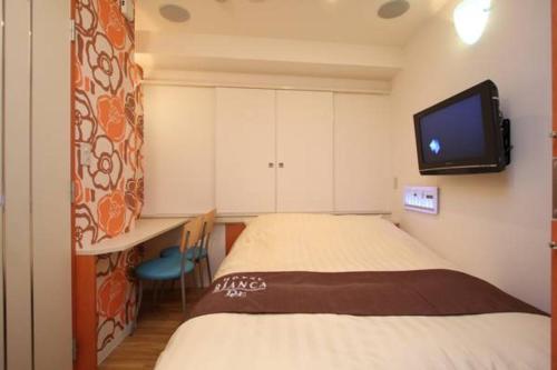 东京比安卡迪尤情趣酒店（仅限成人入住）的卧室配有一张床,墙上配有电视。