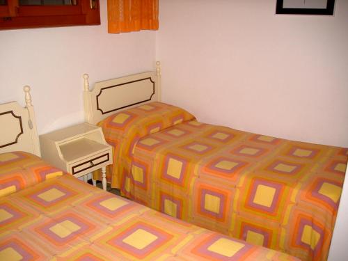 格拉多Nettuno 53的一间卧室配有两张床、一张桌子和一张床套。