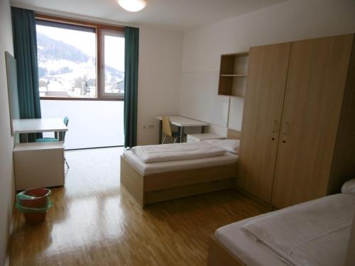 塔姆斯韦格Jugendherberge Tamsweg的客房设有两张床、一张桌子和一个窗户。