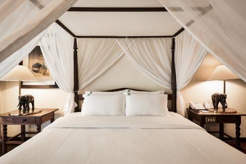 内罗毕赛法瑞公园酒店的一间卧室配有白色寝具和2个床头柜。