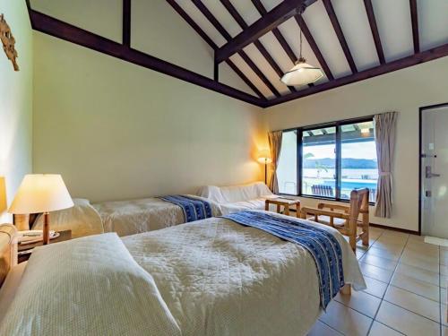 西表岛乌纳里扎奇别墅的一间带三张床的卧室,享有海景