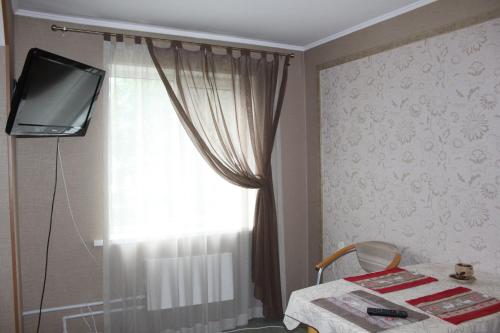 Leninsk-KuznetskiyШевцовой, 10的客房设有带桌子和电视的窗户。