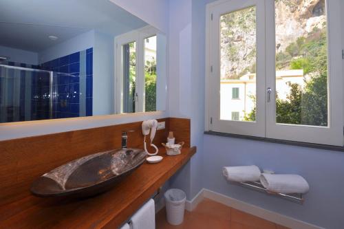 阿马尔菲卡萨茂旅馆的一间带大水槽的浴室和两个窗户