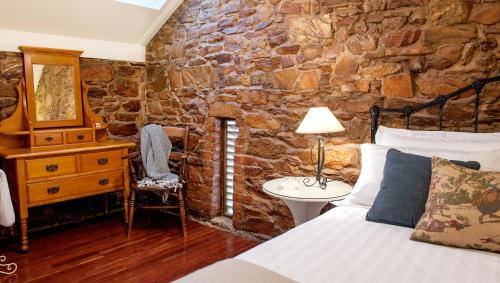 本迪戈拜伦斯瓦尔葡萄园和住宿的一间卧室设有石墙、一张床和一张书桌