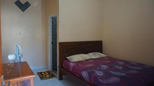 卡里蒙贾瓦Arriani Homestay的一间卧室配有一张床和一张带风扇的桌子。