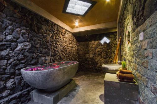 乌布杰罗瑟巴厘别墅的石质浴室设有大浴缸和卫生间。