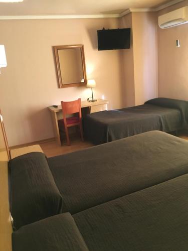 莱加内斯莱加内斯阿文尼达酒店的酒店客房,配有两张床、一张桌子和一把椅子