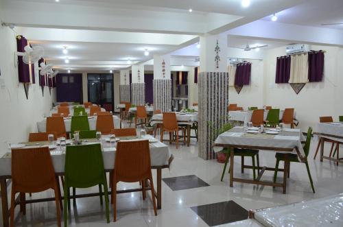 菩提伽耶Hotel Bodh Vilas的一间在房间内配有桌椅的餐厅