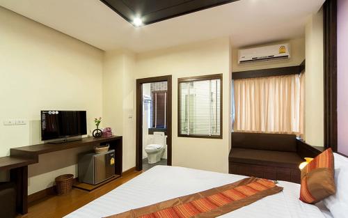 曼谷Tara Place Hotel Bangkok的一间卧室配有一张床、一台电视和一间浴室。