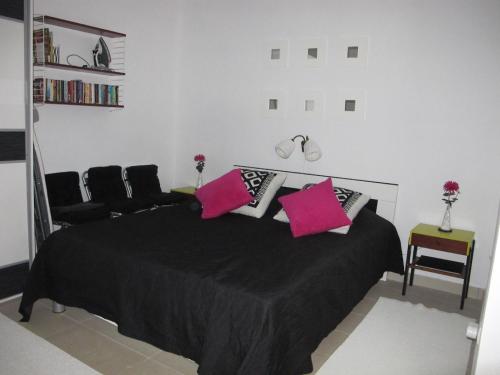 蒂瓦特Apartment Annika的一间卧室配有黑色床和粉红色枕头