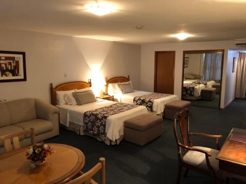 蒙得维的亚水晶宫殿酒店的酒店客房设有两张床、一张沙发和一张桌子。